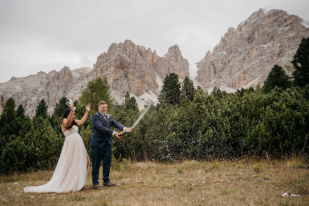 Couple celebrating with champagne in mountain setting.