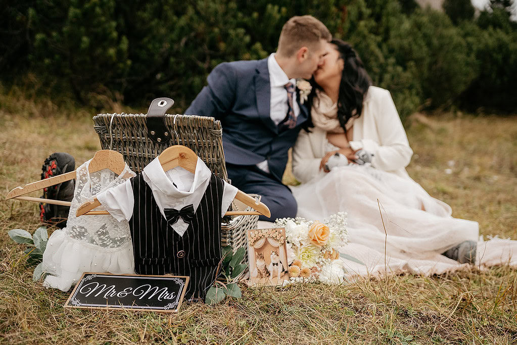 Couple kissing outdoors with wedding decor.