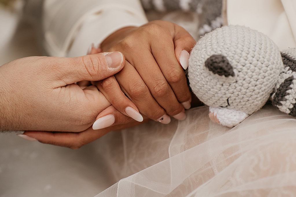 Two hands holding, crochet cat in background.