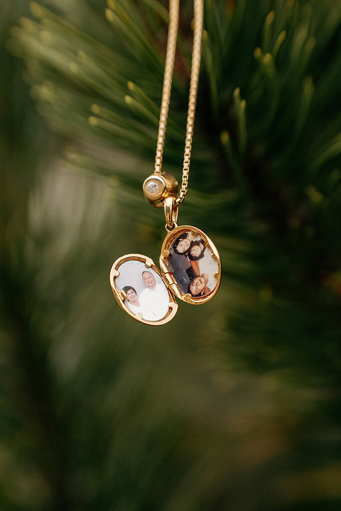 Golden locket with family photos on pine tree.