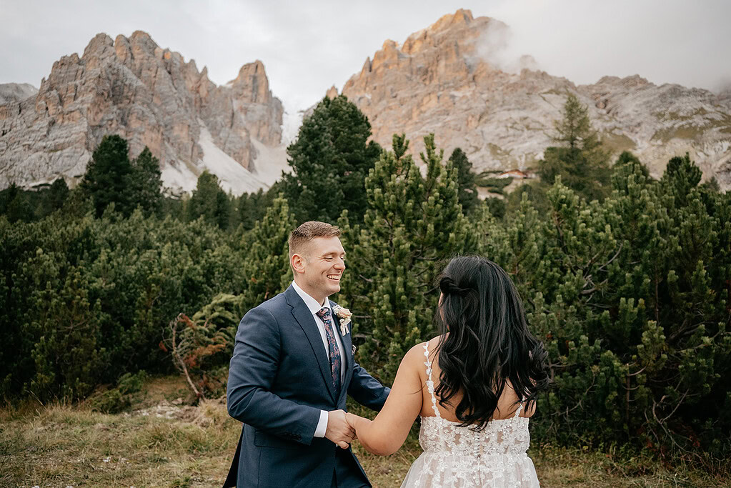 Couple holding hands in mountain landscape.
