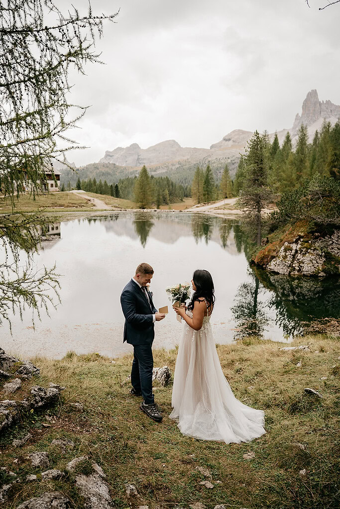 Couple exchanging vows by mountain lake.