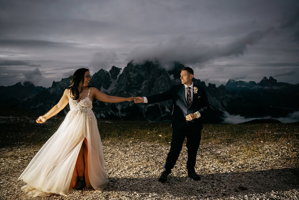 Couple dancing in front of mountain scenery at dusk.