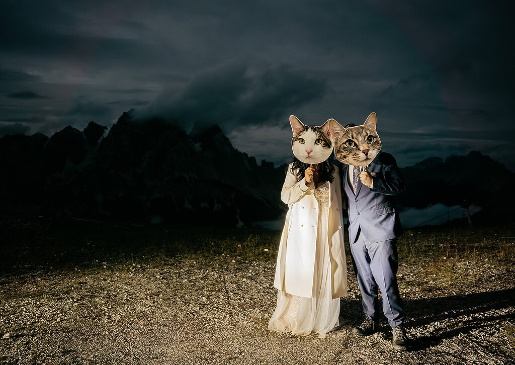 Couple wearing cat masks in mountain landscape.