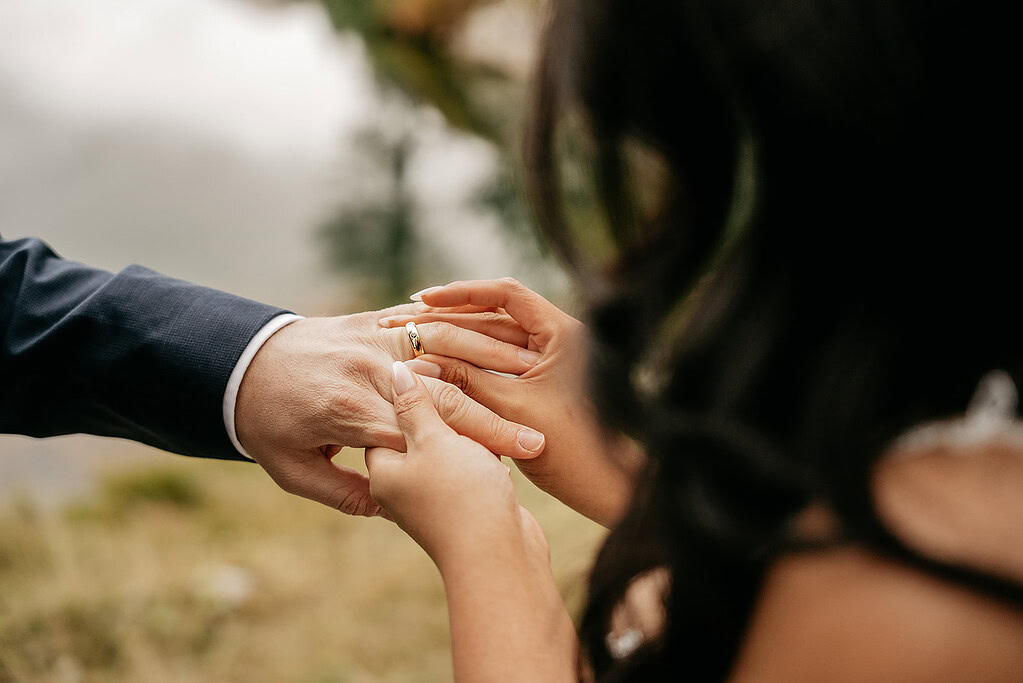 Couple exchanging wedding rings outdoors.