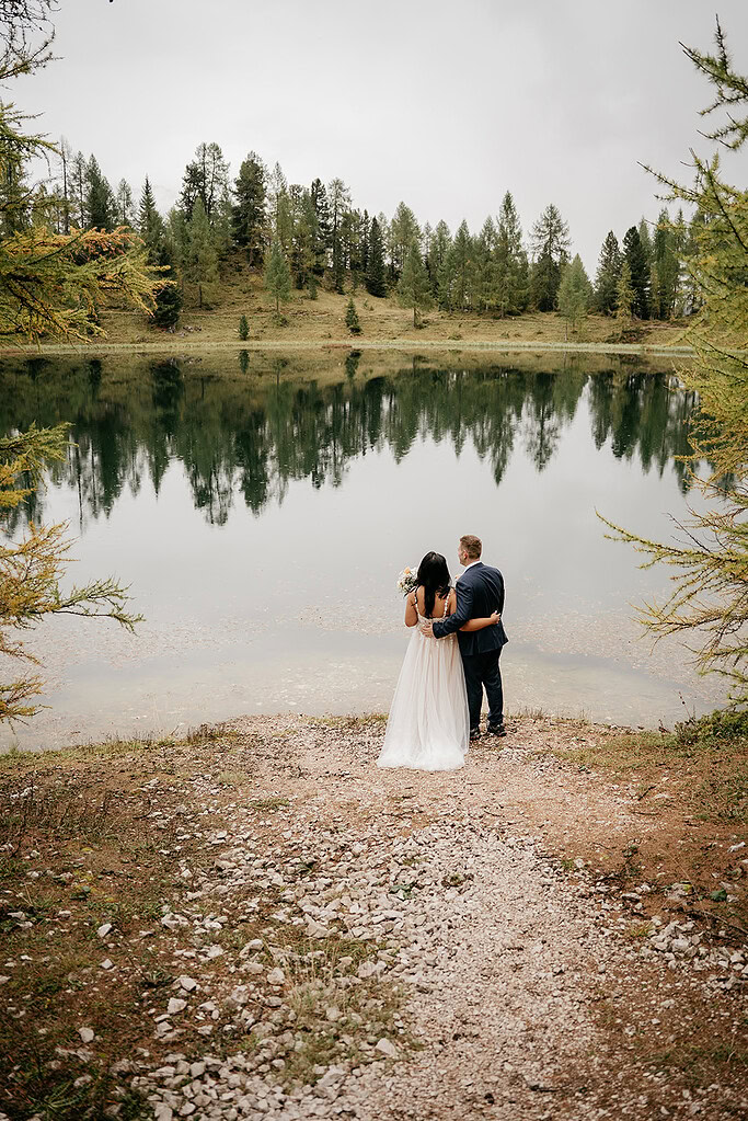 Couple embracing by serene forest lake reflection view.