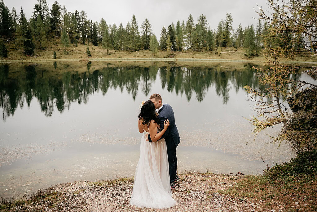 Couple kissing by a serene lakeside view.