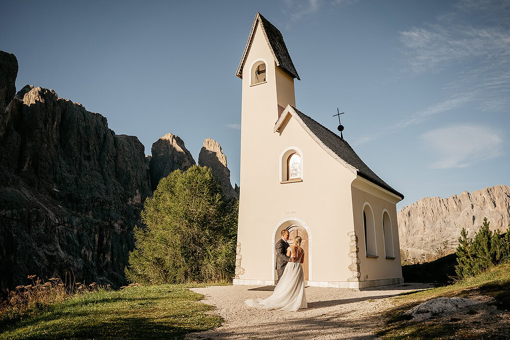 Couple at chapel in mountains during wedding ceremony.
