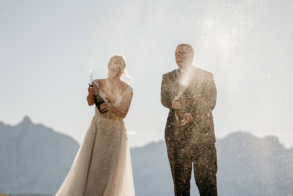 Bride and groom spraying champagne outdoors