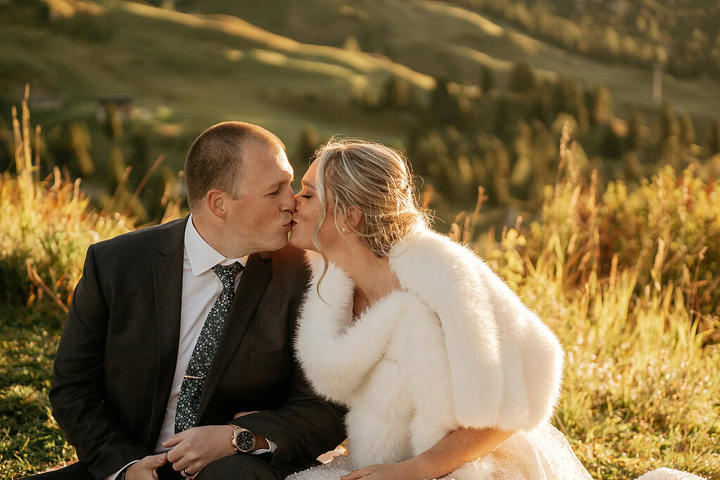 Couple kisses in scenic outdoor wedding setting.