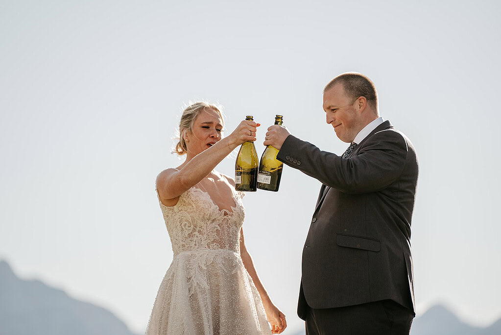 Bride and groom celebrating with champagne toast outdoors.