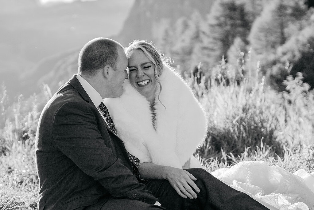 Smiling couple embraces outdoors in wedding attire.