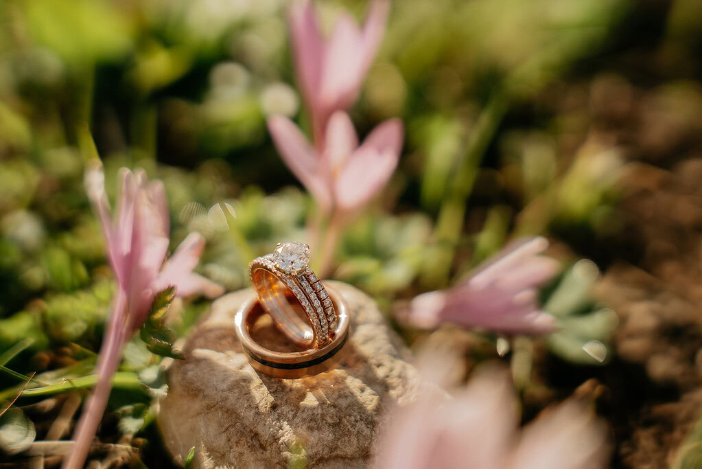 Diamond and gold rings on rock with flowers