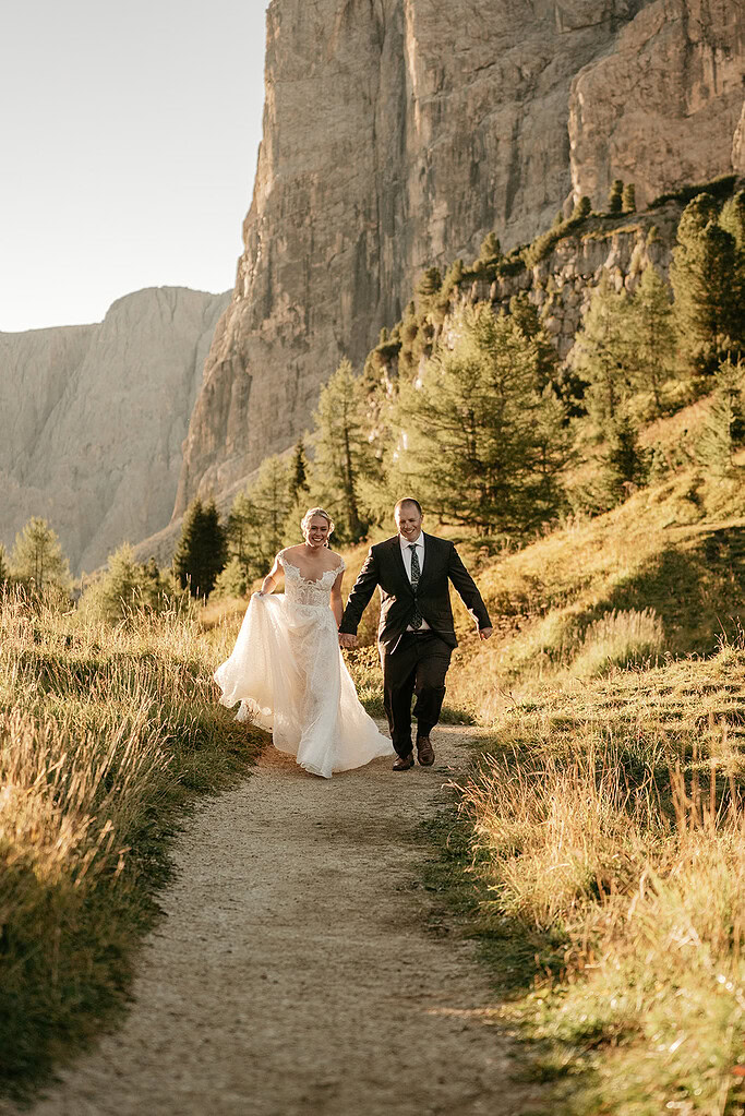 Bride and groom hiking on mountain path