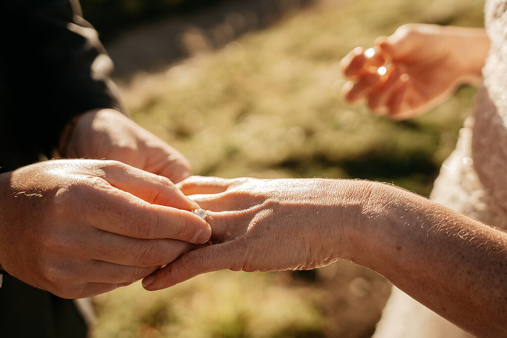 Close-up of person placing ring on finger.